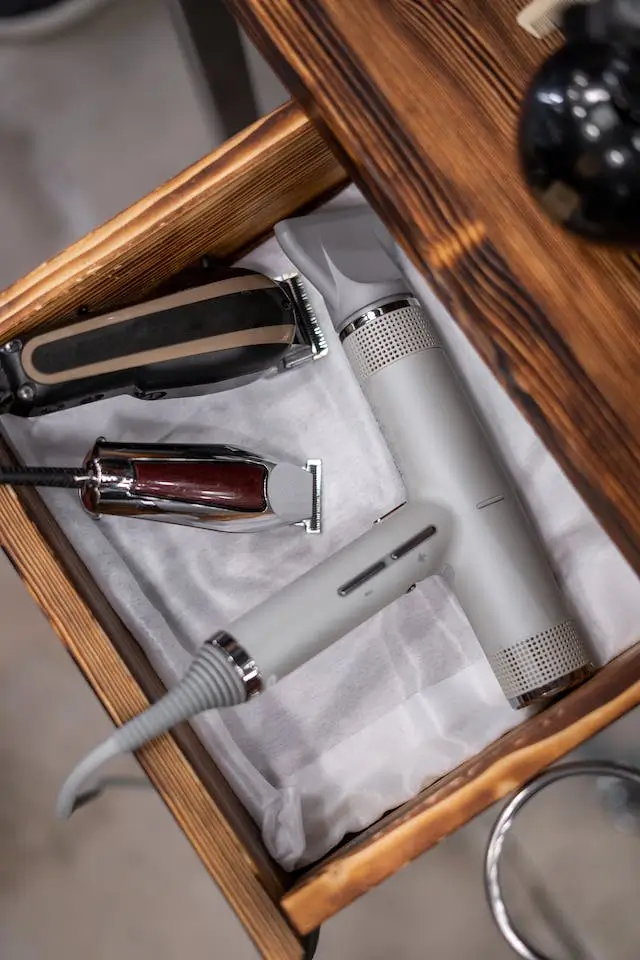 An organized drawer of men's hair styling tools including clippers, scissors, and a blow dryer